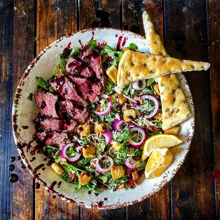 Summer salad topped with sirloin steak and balasamic