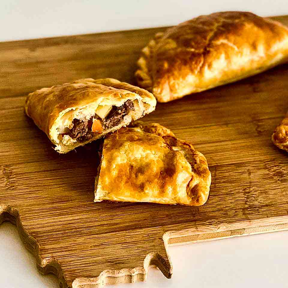 Beef pasties served on a cutting board shaped like Montana.