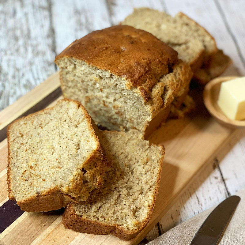 Classic banana bread from Felton Angus Beef displayed on a wooden cutting board with butter.