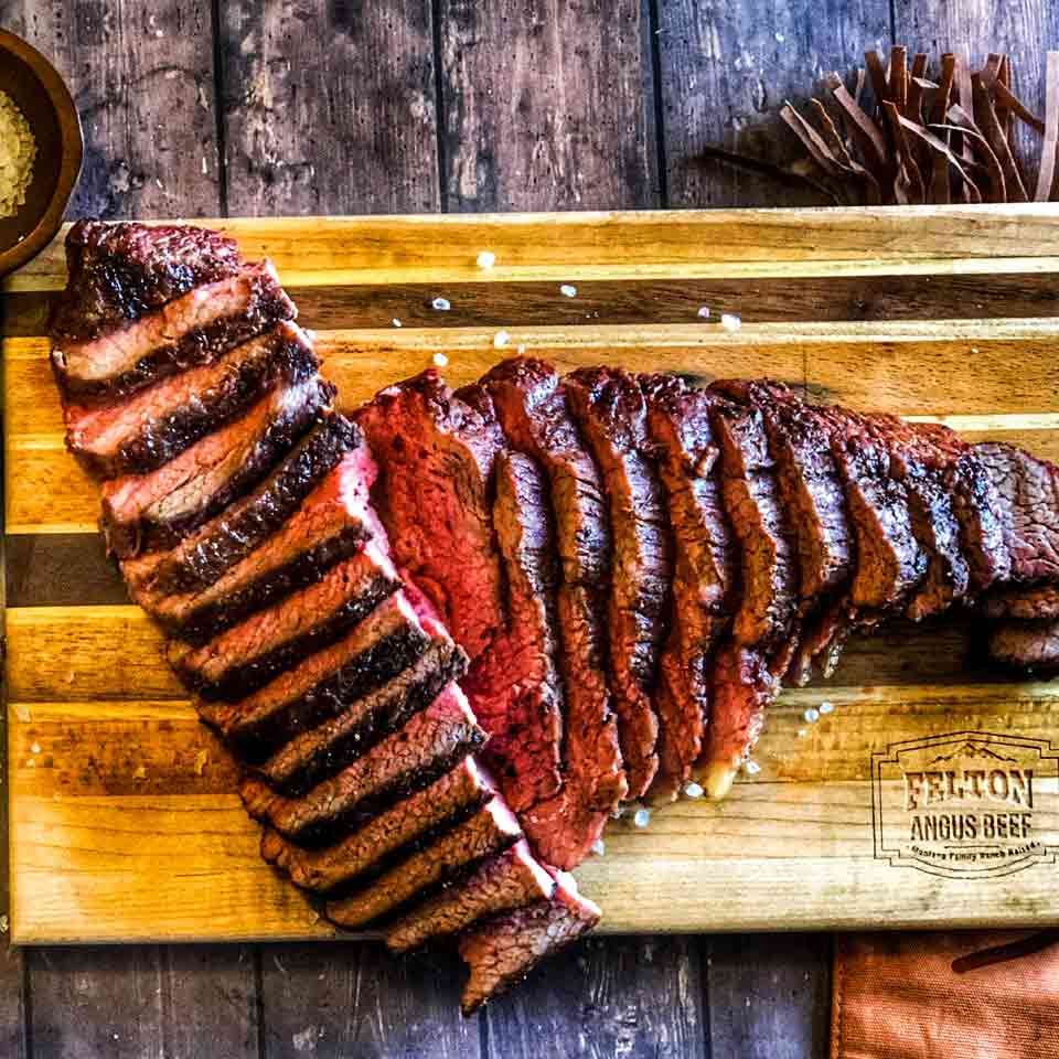 A grilled tri-tip roast from Felton Angus Beef is shown sliced on a cutting board